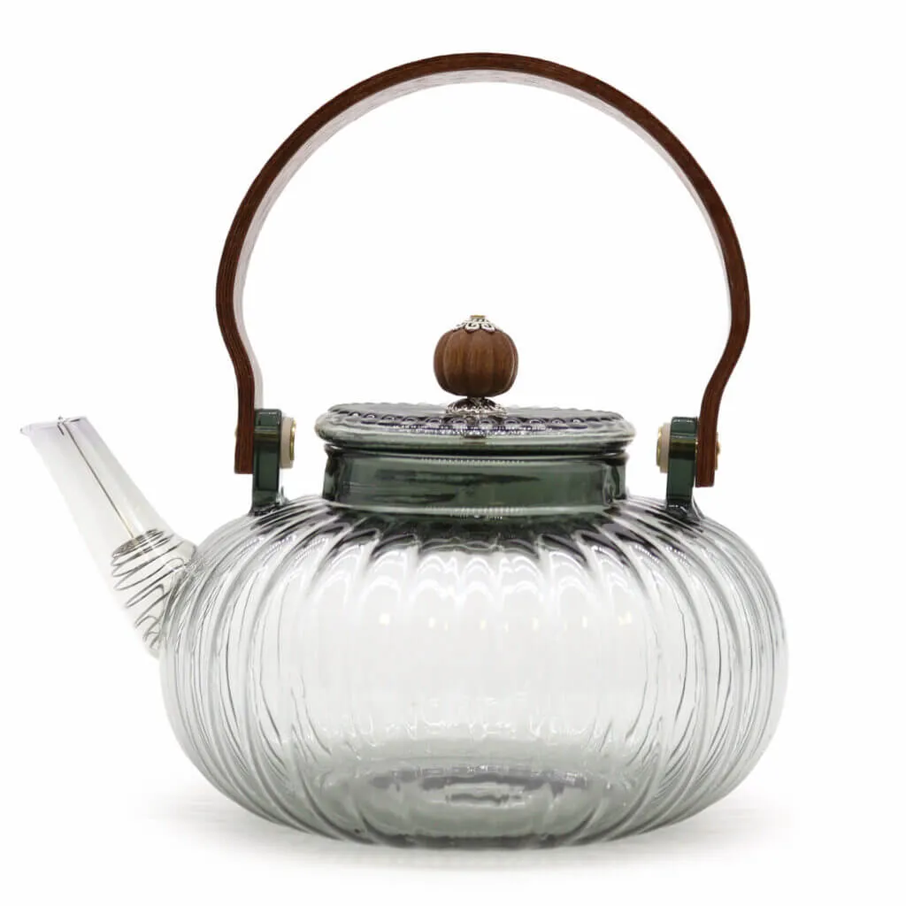 Clear glass teapot with a ribbed design, short spout, metal lid topped with a wood knob, and a curved wooden handle.