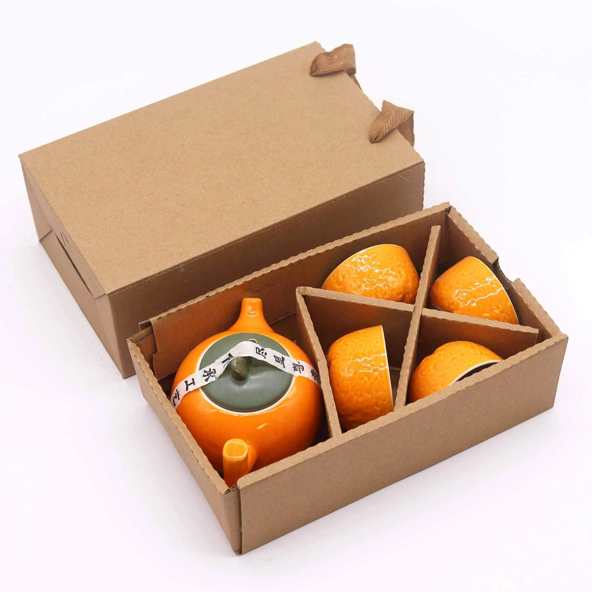 A cardboard box containing an orange teapot and three matching teacups, each with a textured surface, securely arranged in individual compartments.