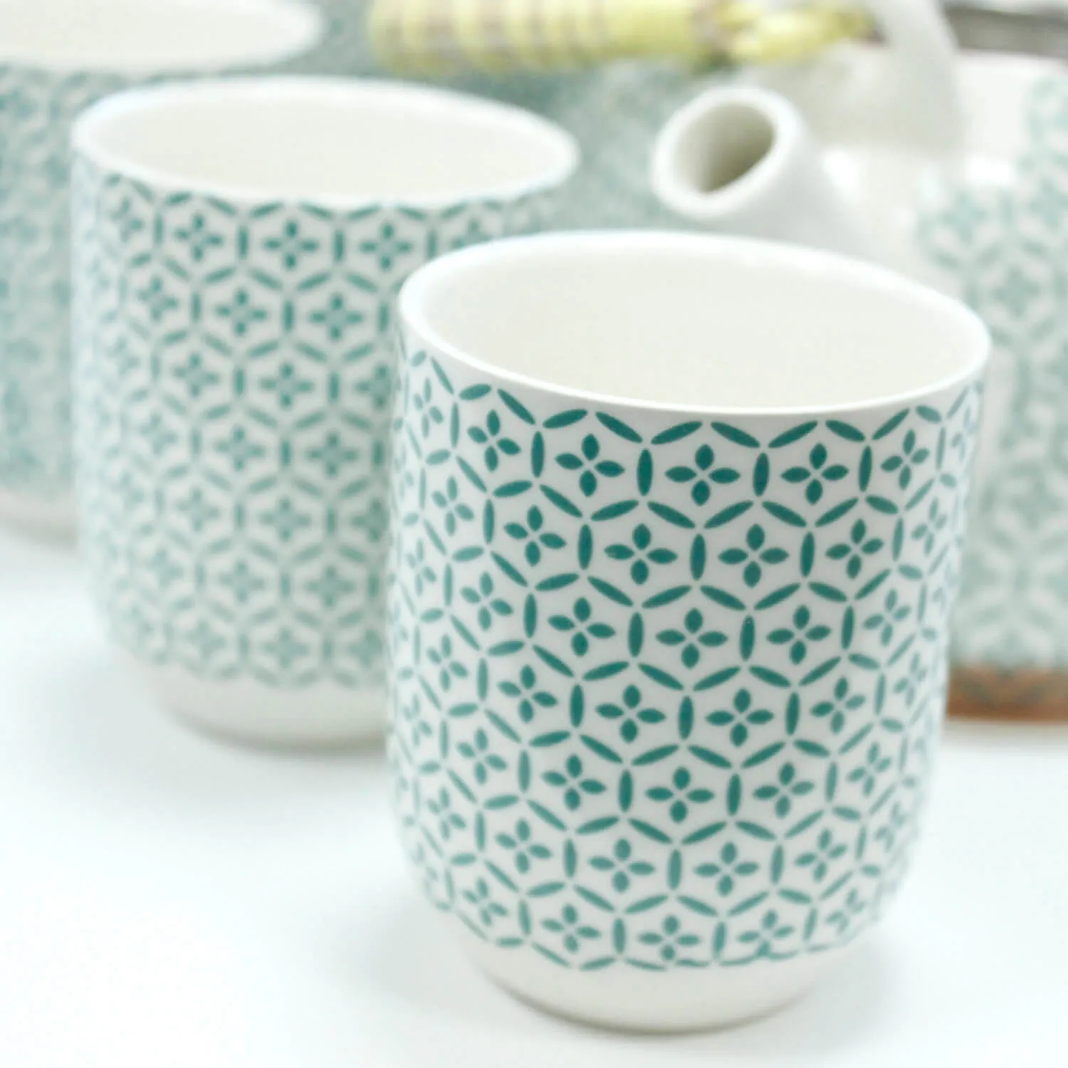 A close-up of patterned ceramic cups with a blue geometric design, arranged on a white surface.