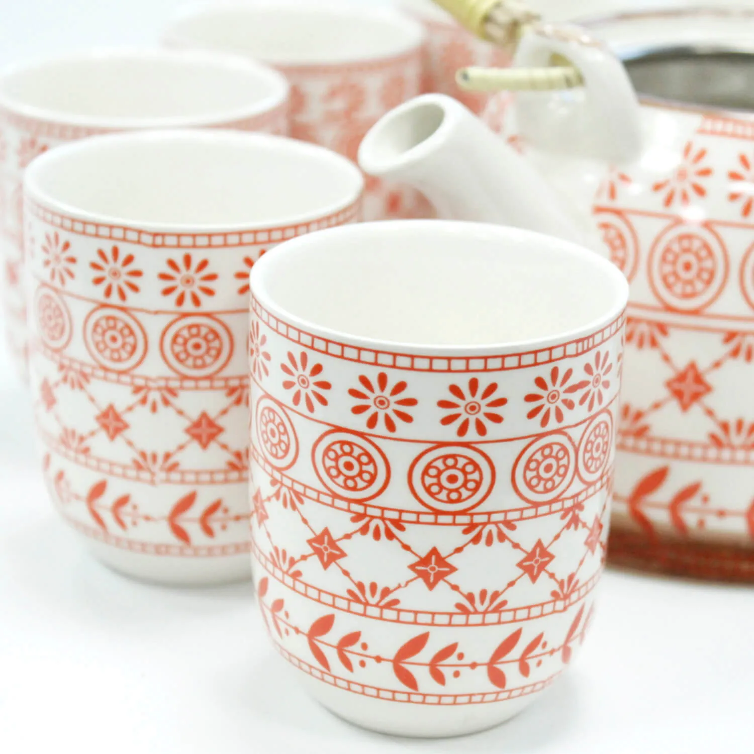 White ceramic tea set with cups and a teapot, all featuring red geometric and floral patterns.