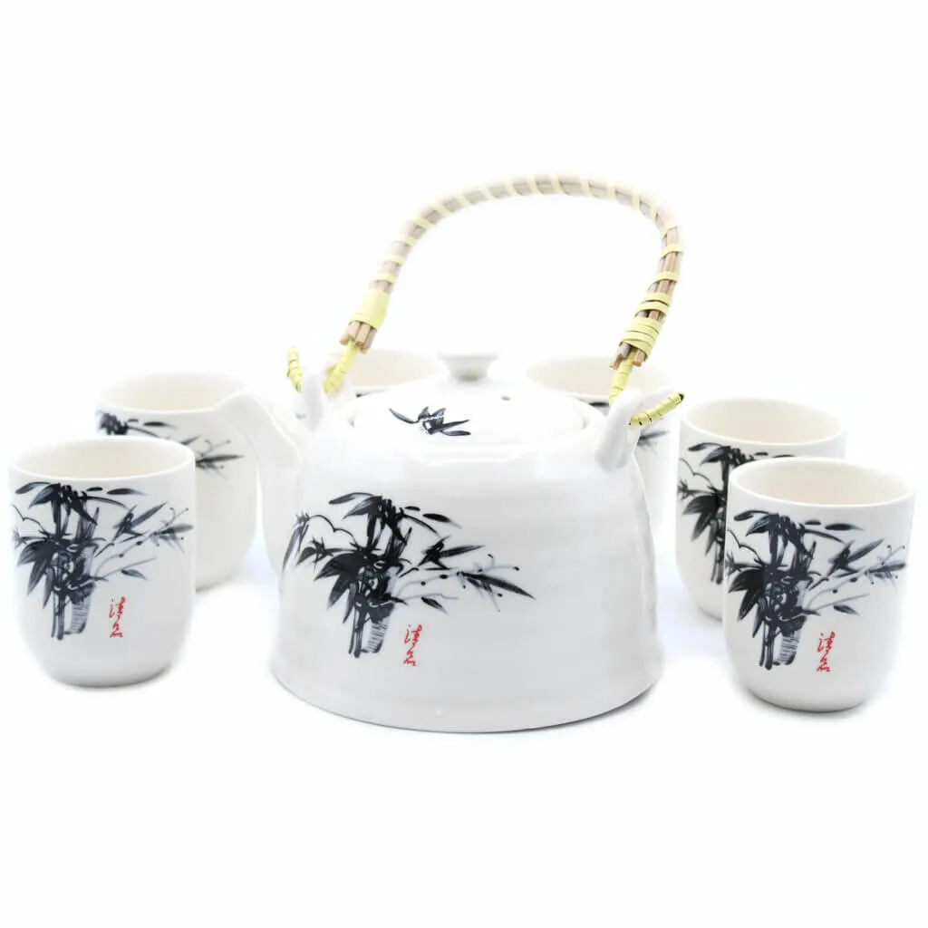 White ceramic teapot with a bamboo handle and four matching cups, all decorated with black bamboo designs and red Asian script.