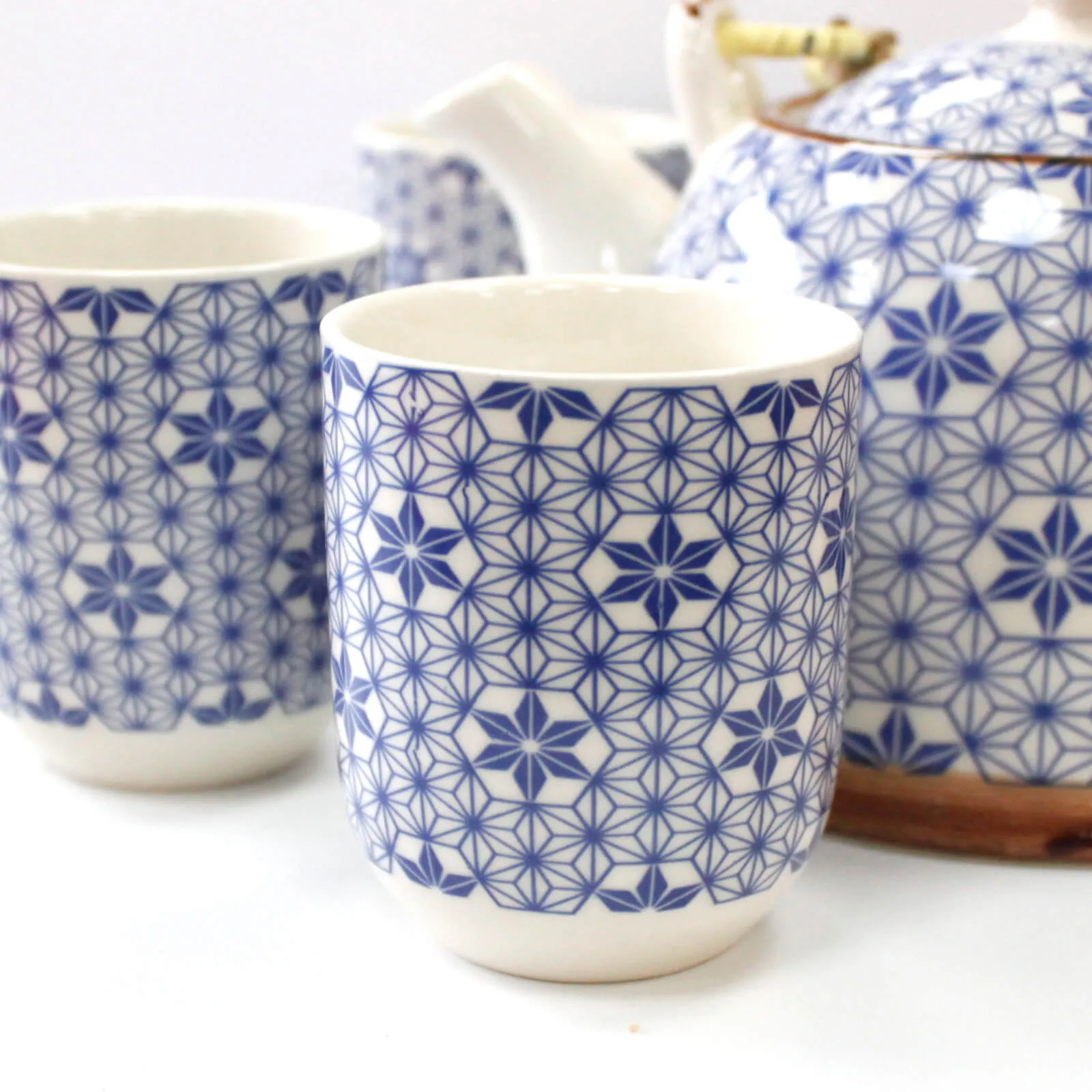 Two ceramic cups and a teapot with blue geometric patterns on a white background.