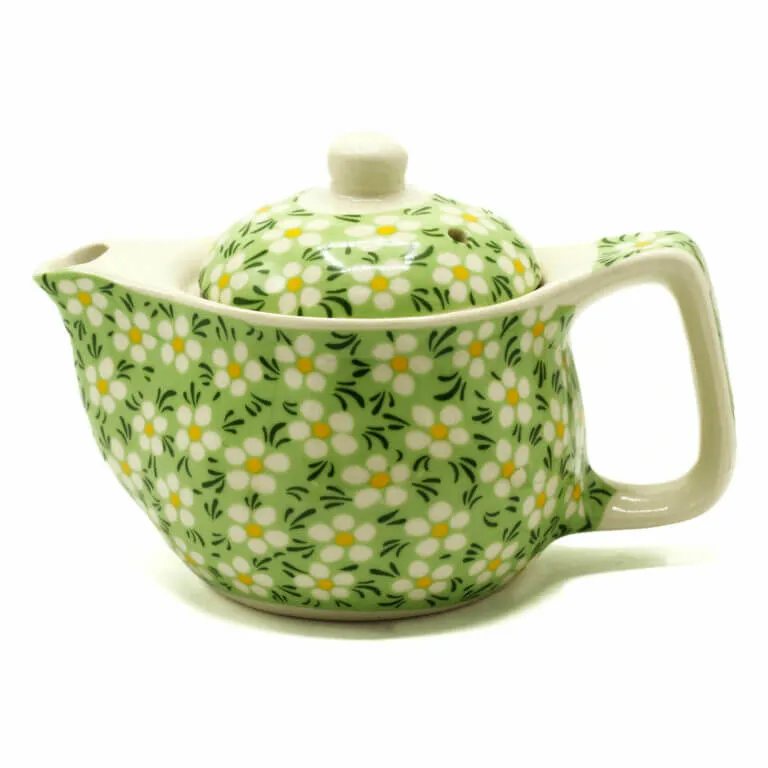 A ceramic teapot with a handle and spout, decorated with a green background and white and yellow floral pattern.