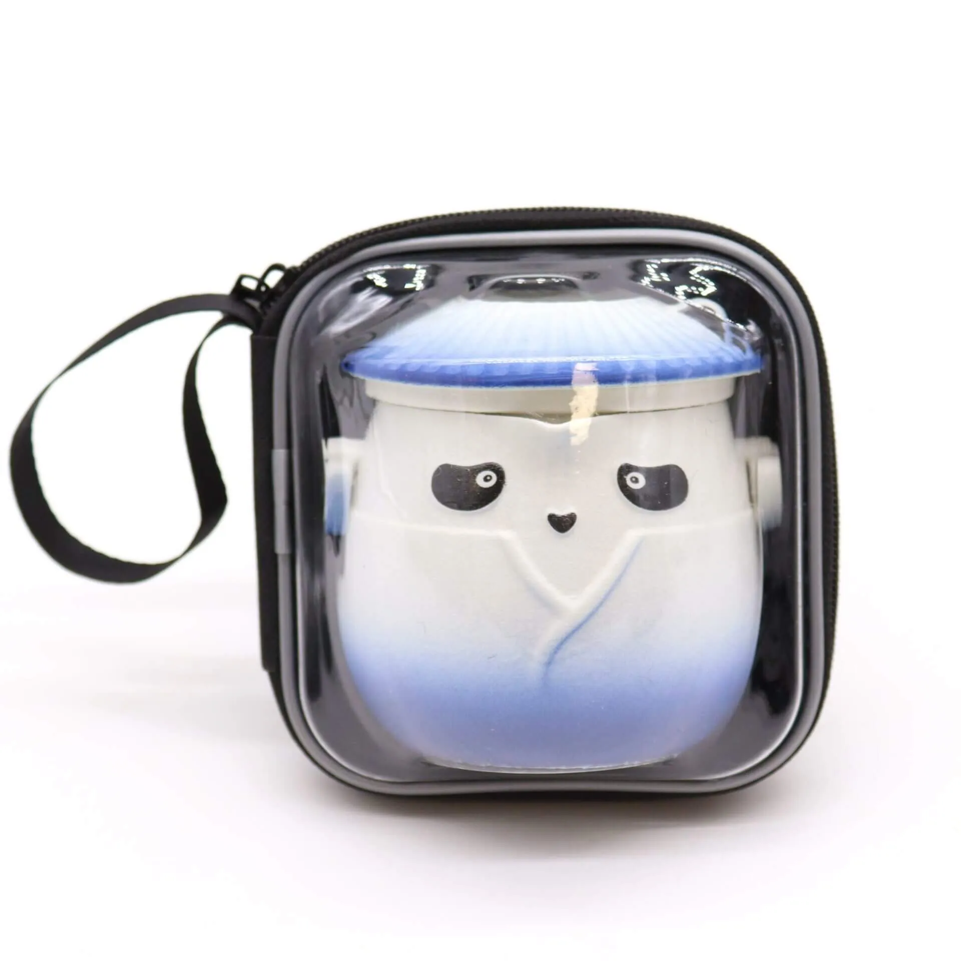 A small ceramic container with a face and blue gradient design, packaged in a square, clear zippered carrying case with a black handle.