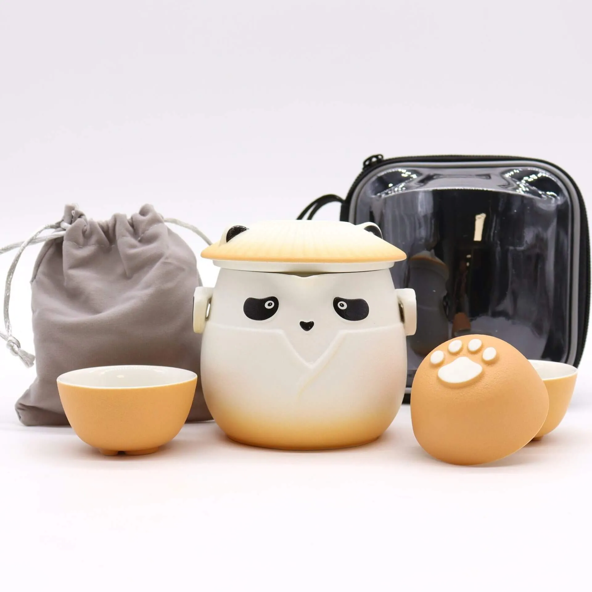 A panda-themed ceramic tea set with a teapot, two cups, a drawstring pouch, and a black carrying case arranged on a white surface.
