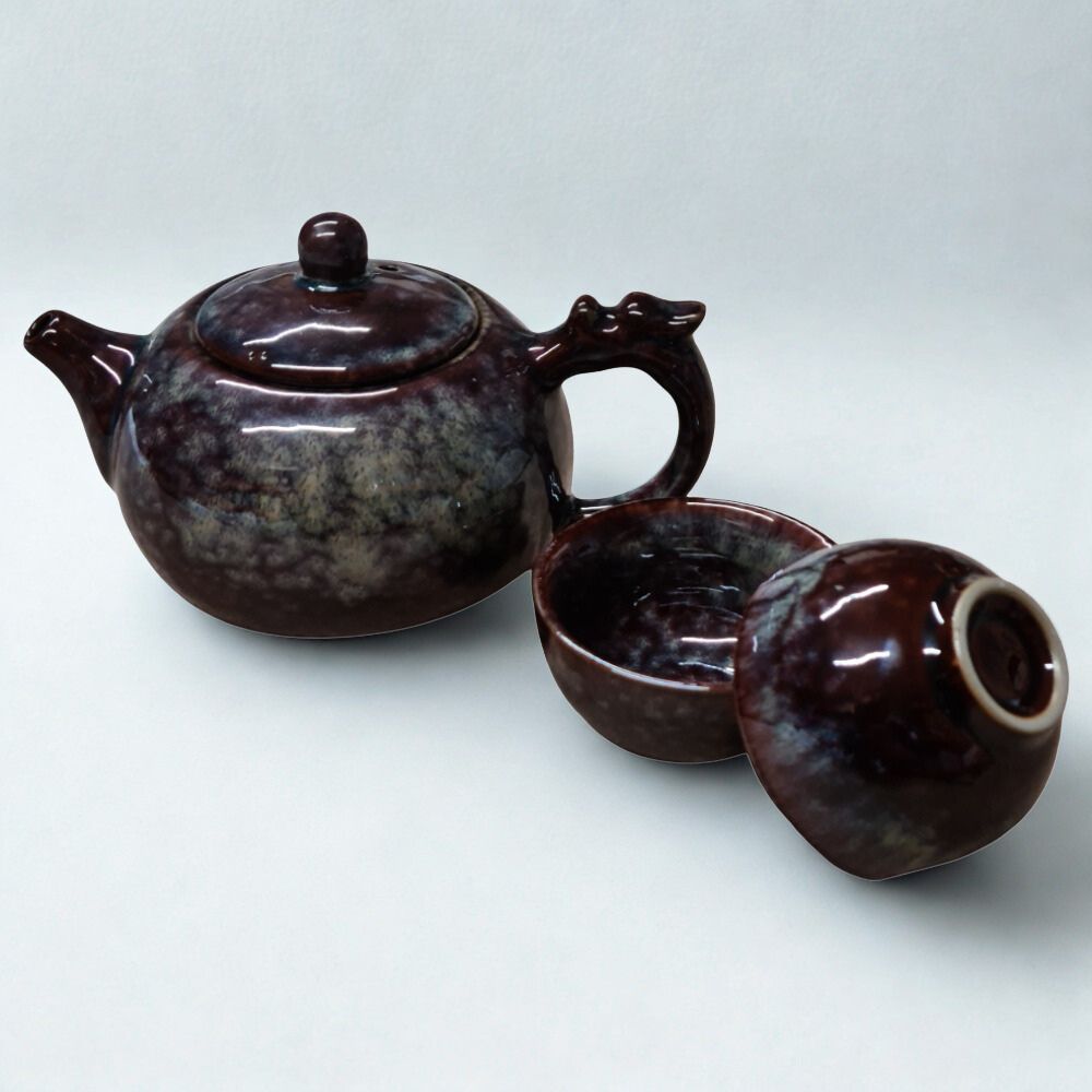 The Ocean Blue Teapot for One is an aqua teal tea set with 2 cups, featuring a glossy marbled finish and round lid, inspired by ocean hues, and elegantly displayed on a plain white background.